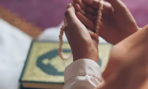 Seorang Muslim sedang berzikir dan berdoa sambil memegang tasbih di tangannya.