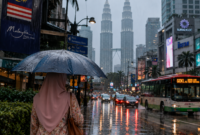 Seorang wanita berjalan menyusuri jalan bandar di bawah payung ketika hujan mencurah-curah